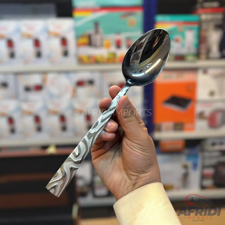 A shiny, silver-colored metal spoon with a patterned handle.