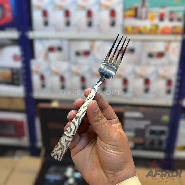 A silver metal fork with a decorative, wavy pattern on its handle.
