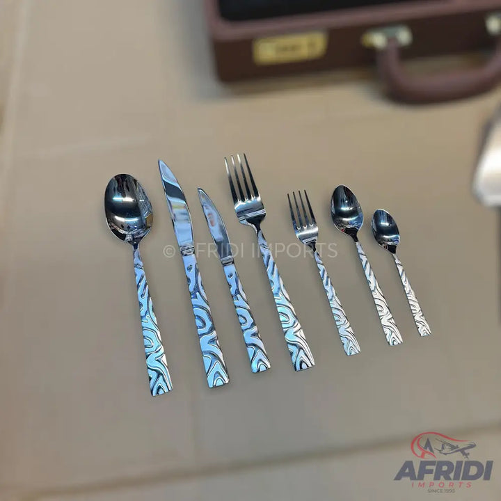 A set of seven polished stainless steel utensils with patterned handles.