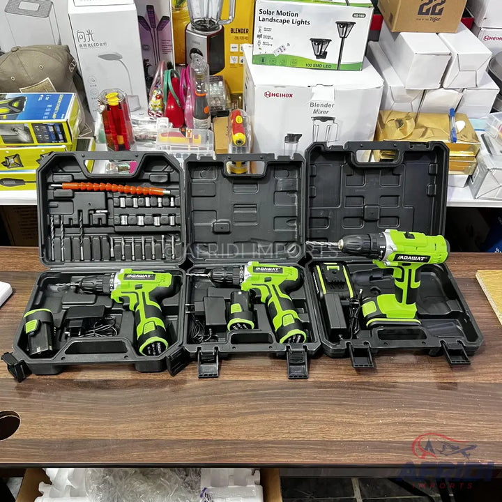 A set of four green and black cordless drills with accompanying accessories and bit sets in black carrying cases.