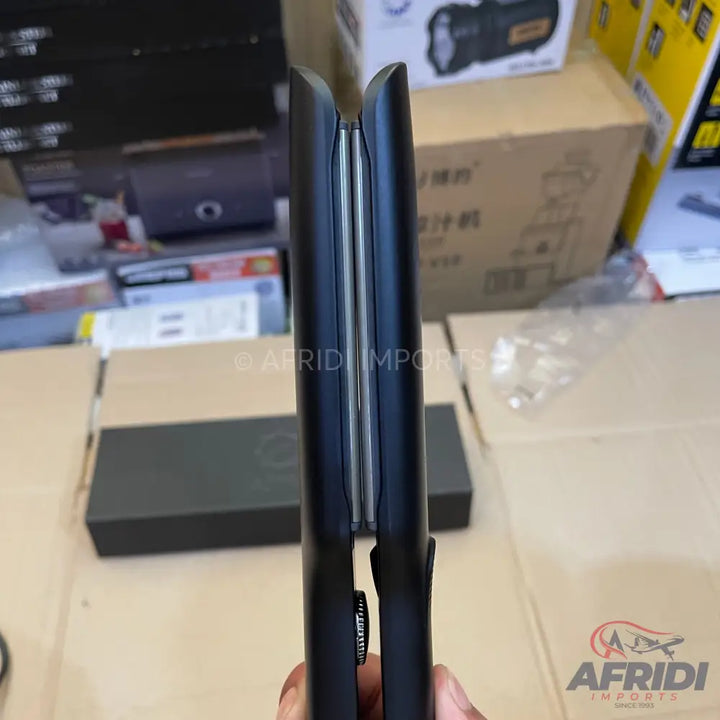 A sleek, black hair straightener with two thin, silver heating plates.