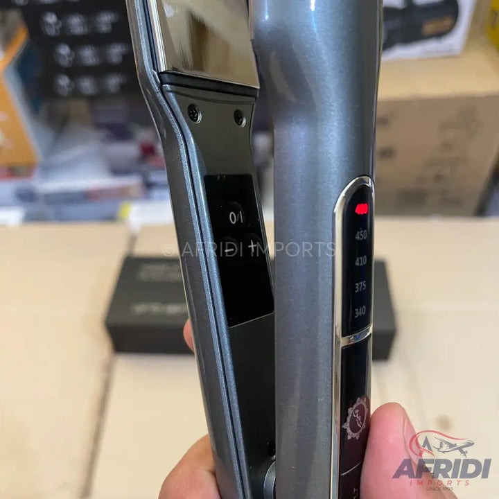 A gray hair straightener with digital temperature control and an illuminated indicator light.