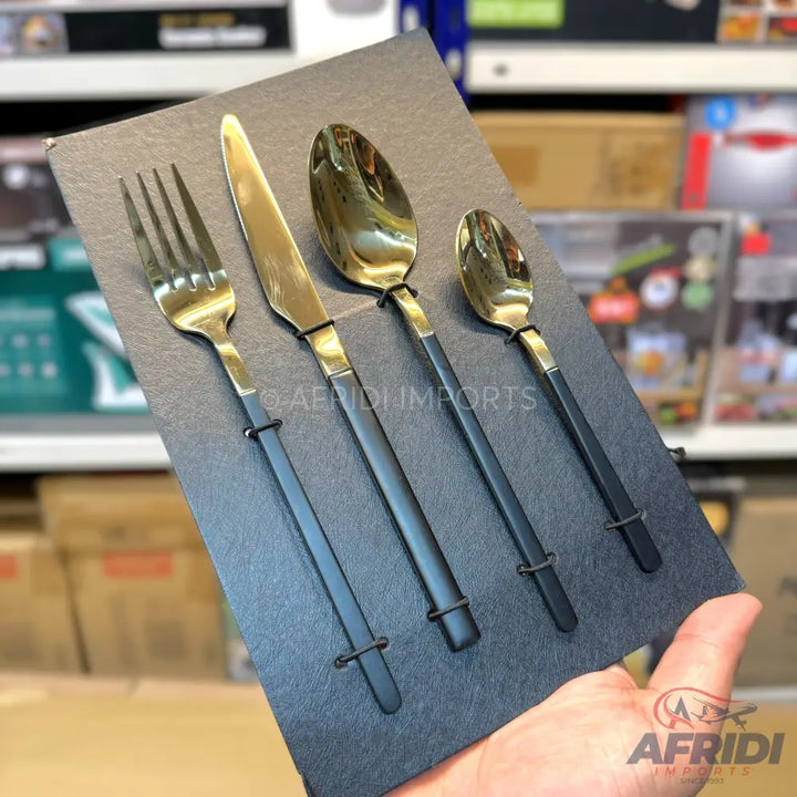 A four-piece set of gold and black flatware, including a fork, knife, tablespoon, and teaspoon.