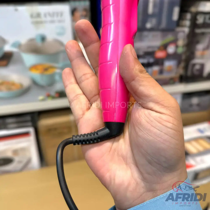 Pink hair curling iron with a black power cord.