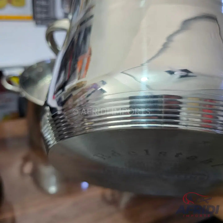 Shiny, reflective metal pot with horizontal ridges.
