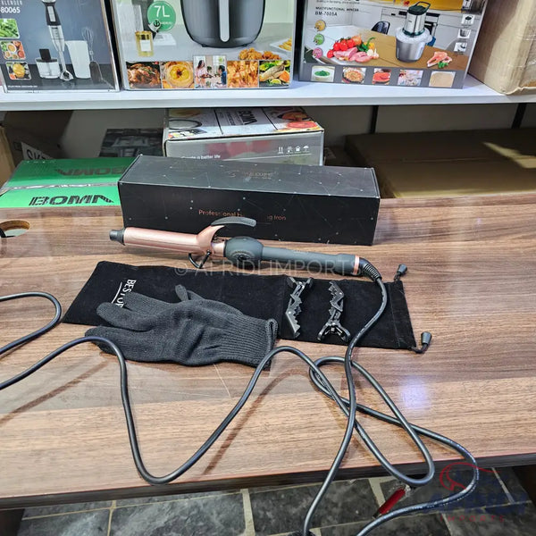 Rose gold curling iron with a black handle, accompanied by a black heat-resistant glove and two hair clips.
