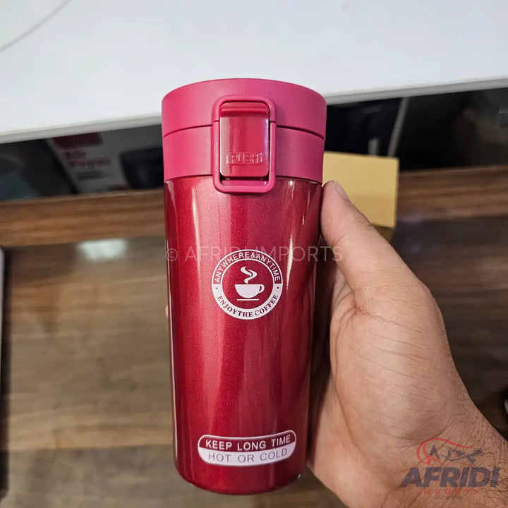 A red insulated travel mug with a push-button lid.