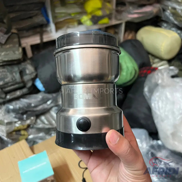 Stainless steel electric coffee grinder with a black lid and switch.