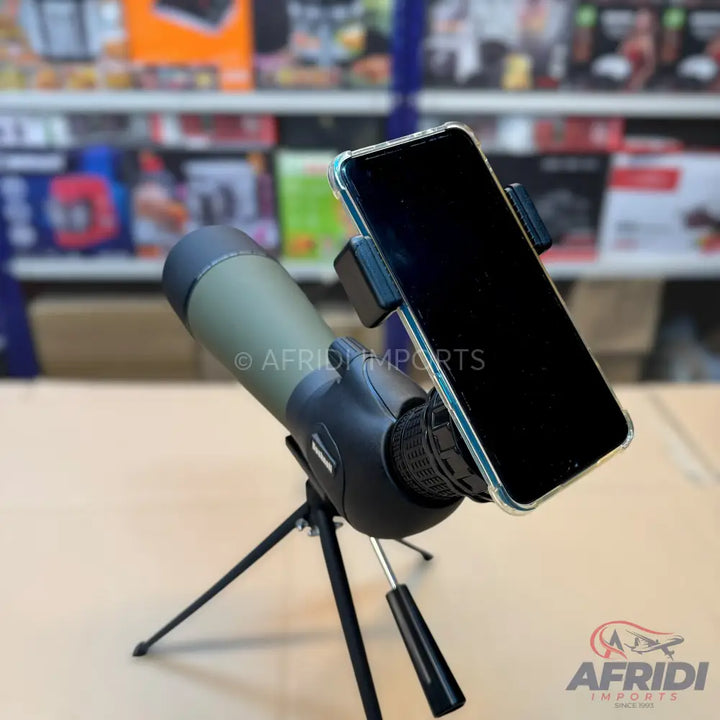 An olive green monocular on a tripod with a smartphone attached for viewing.