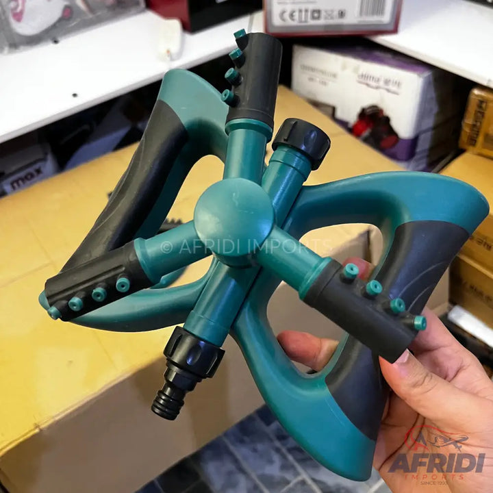 Teal and black plastic garden sprinkler with three rotating arms and multiple nozzles.
