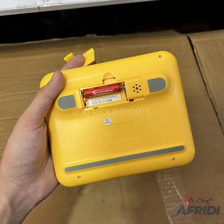 Yellow electronic scale with an open battery compartment revealing two red AAA batteries.