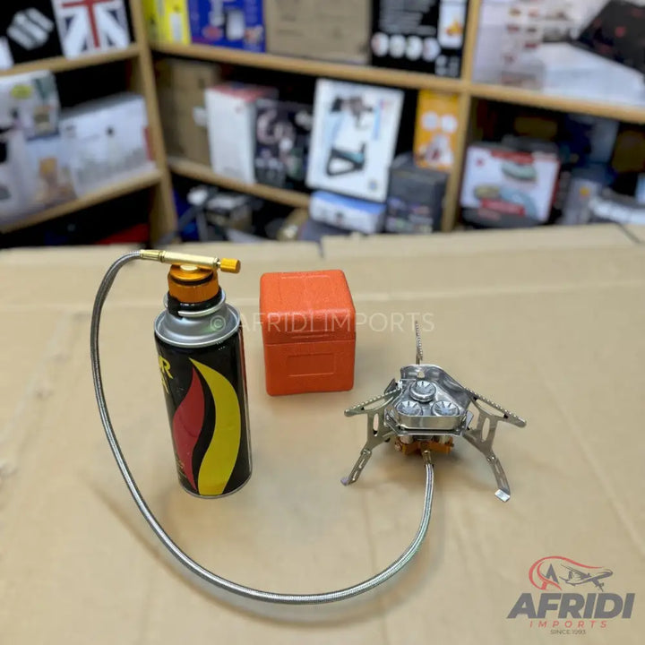 Portable camping stove with a connected fuel canister and an orange carrying case.