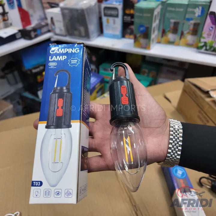 A black camping lamp with a clear, elongated bulb and a red power button, featuring a top hook for hanging.