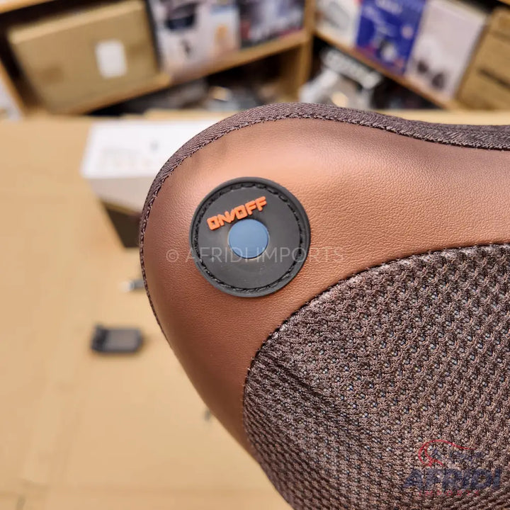 Close-up of a brown and grey textured foot massager with an on/off button.