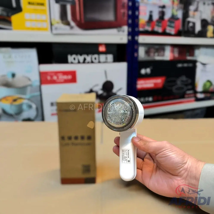 White handheld fabric shaver with a clear lint collection compartment.