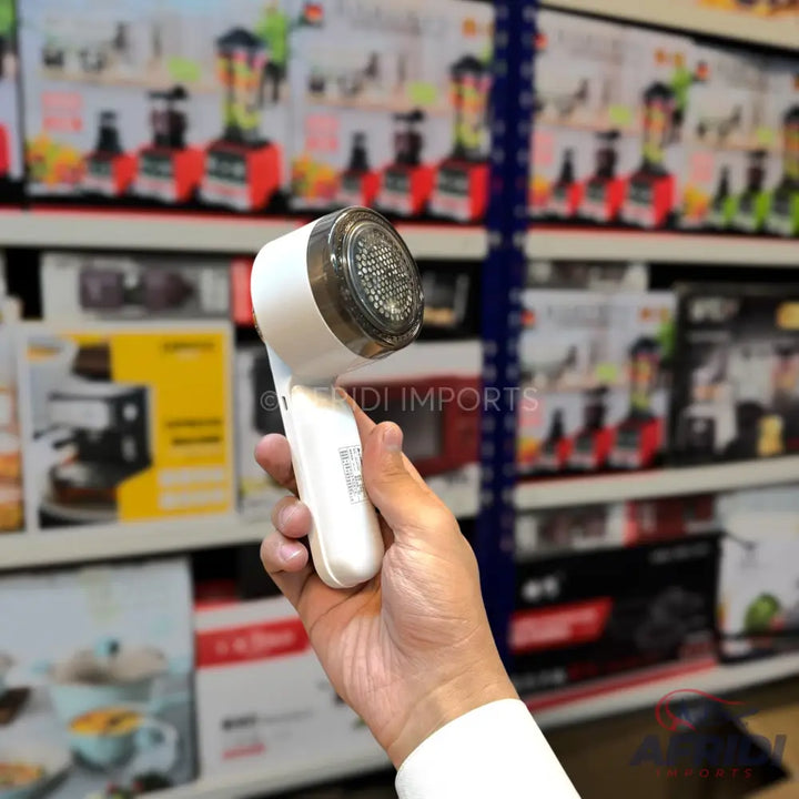 White handheld fabric shaver with a clear, perforated cap.