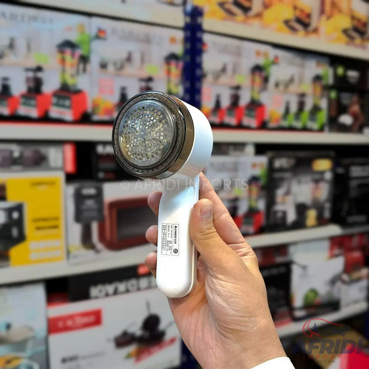 A white, handheld lint remover with a clear, perforated cover.