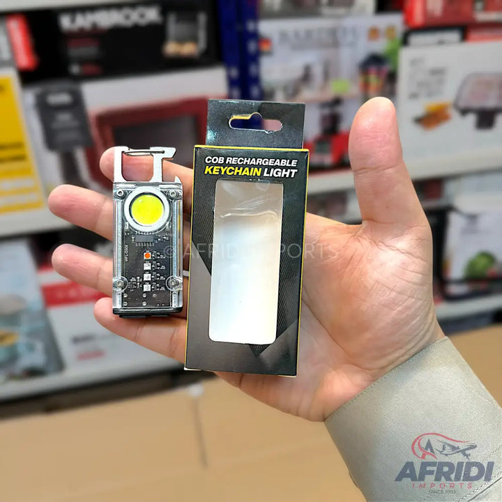 A transparent rectangular COB rechargeable keychain light with an integrated carabiner clip.