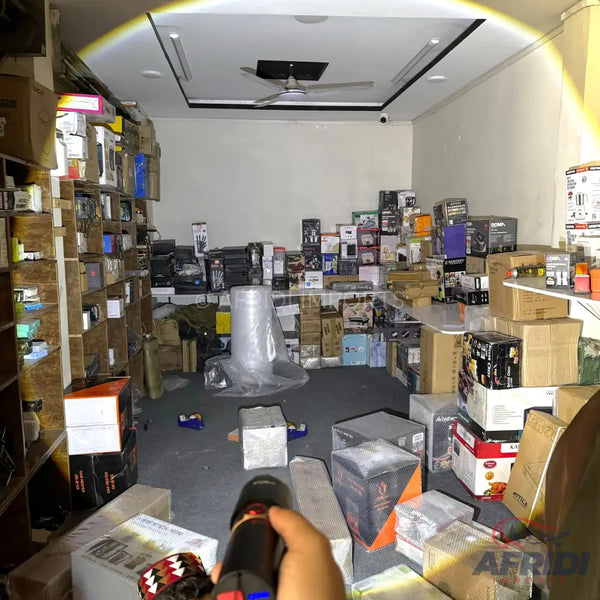 A person holding a flashlight in a room filled with boxed goods.