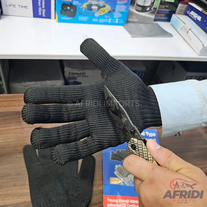 Black cut-resistant glove being tested with a knife.