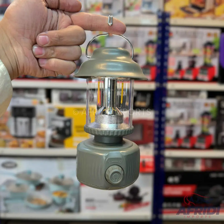 A gray, vintage-style lantern with a clear glass body and a rotary switch.