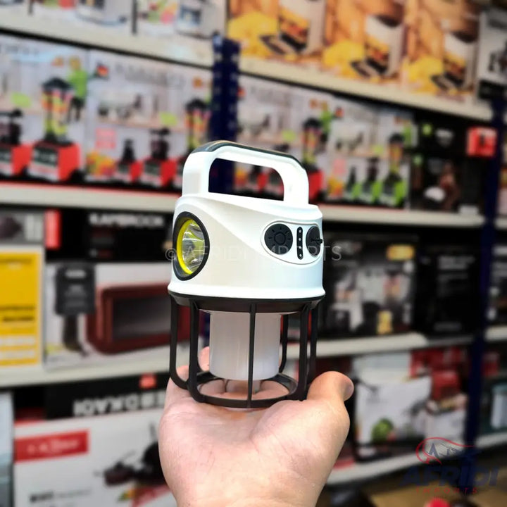 A white and black multi-functional camping lantern with a spotlight and a floodlight, featuring a top handle and side controls.
