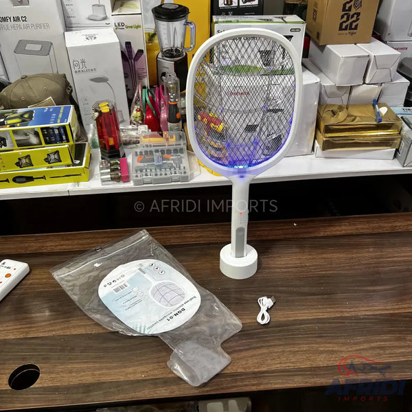 White electric fly swatter with a charging base and a blue light.