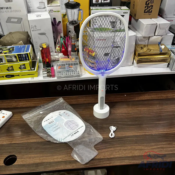 White electric fly swatter with a charging base and a blue light.