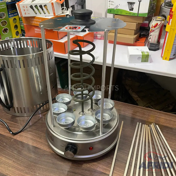 A stainless steel hot dog roller grill with a spiral heating element and multiple bun warming cups.