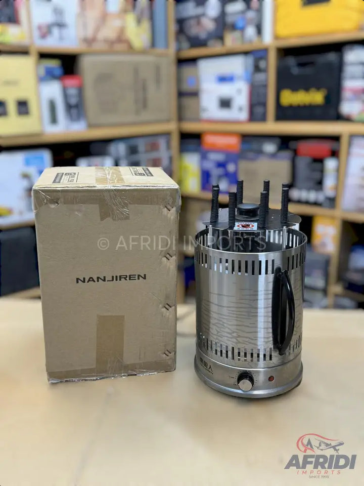 Silver-colored electric vertical rotisserie grill with multiple skewers, accompanied by its cardboard packaging.