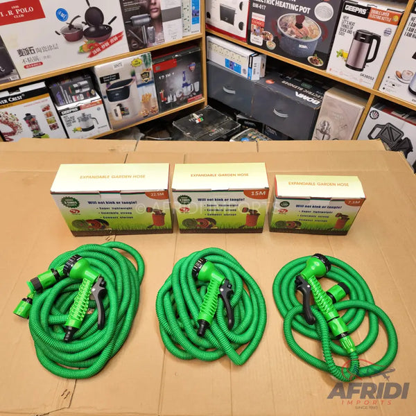 Three coiled green expandable garden hoses with spray nozzles, each in its individual box.