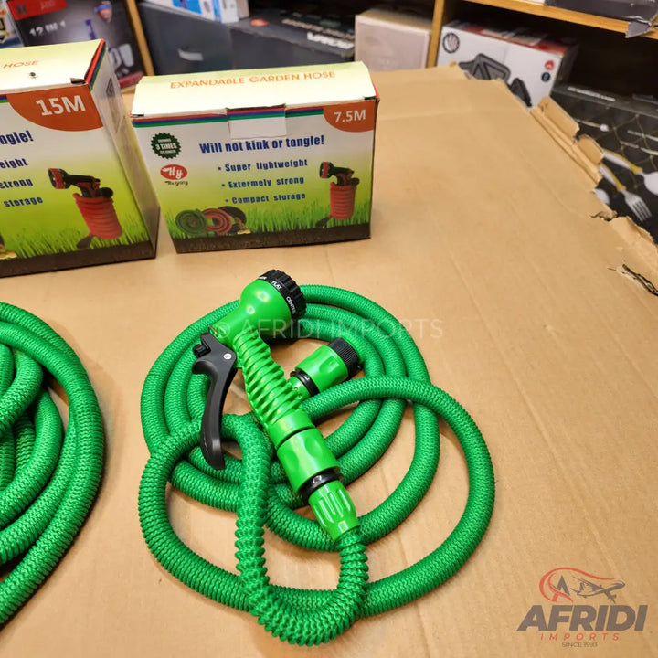 Green expandable garden hoses with spray nozzles, packaged in boxes.