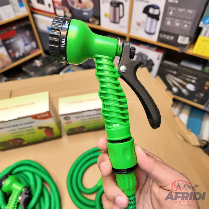 Green expandable garden hose with a multi-pattern spray nozzle and trigger handle.