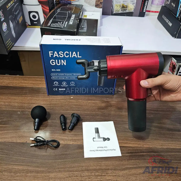 Red handheld percussive massage gun with multiple interchangeable heads and a charging cable.