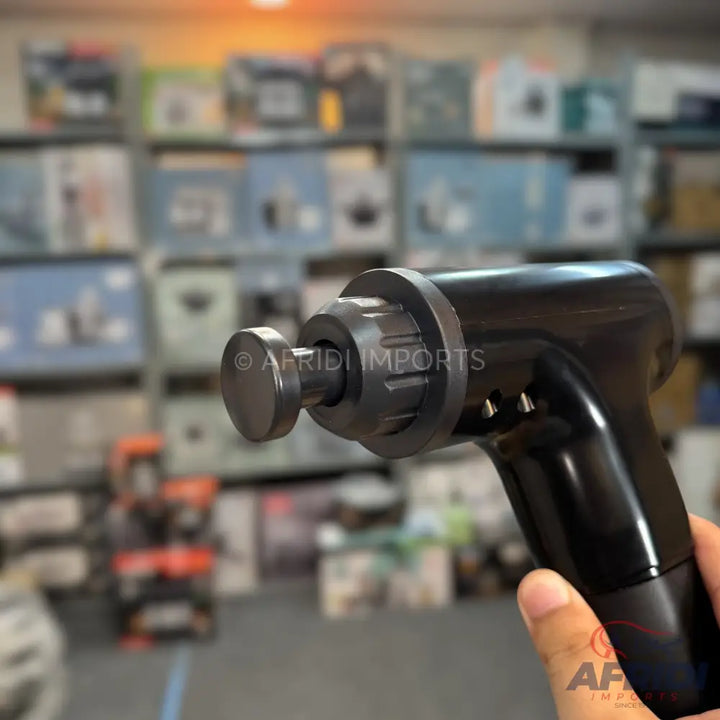 Black handheld massage gun with a round head attachment.