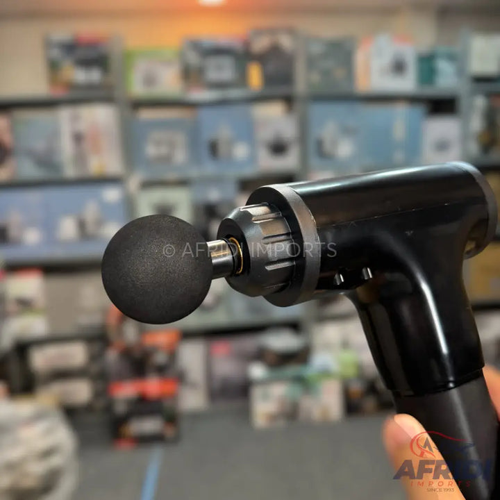 Black handheld percussion massage gun with a spherical attachment.