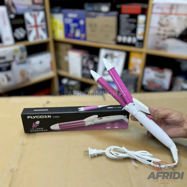 A white and pink electric hair curler with a power cord, held by a hand.