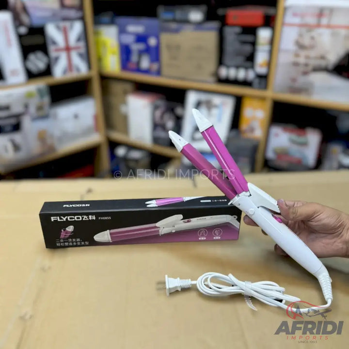 A white and pink electric hair curler with a power cord, held by a hand.