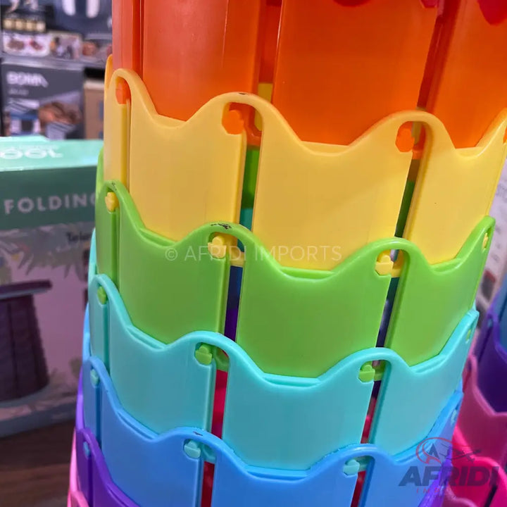 A stack of colorful, collapsible plastic baskets in a rainbow of hues.