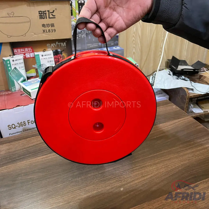 Red circular portable folding stool with a black strap handle.
