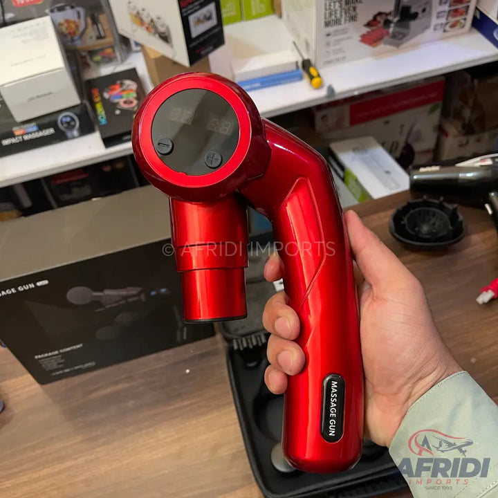 A shiny red handheld massage gun with a black digital display and control buttons.