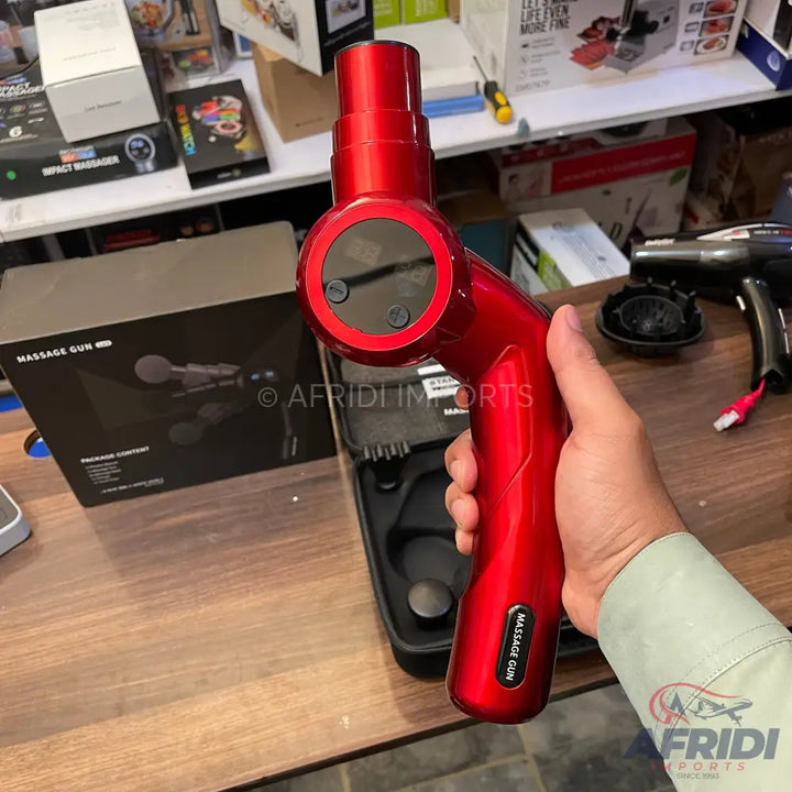 Red handheld percussive massage gun with a digital display.