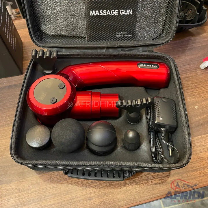 Red percussion massage gun with multiple interchangeable heads and a charger in a carrying case.