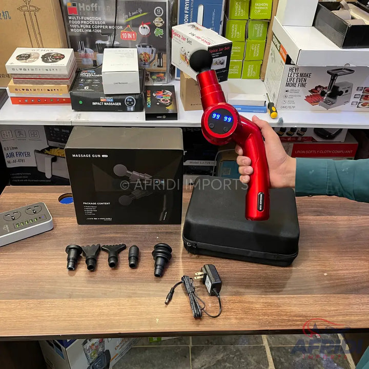 Red percussive massage gun with multiple interchangeable heads and a charger.