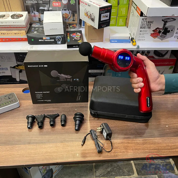 Red handheld percussion massage gun with multiple interchangeable heads and charger.