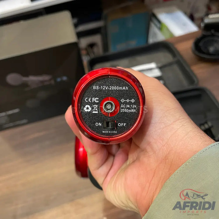 Red handheld electric massager with a power switch and charging port.