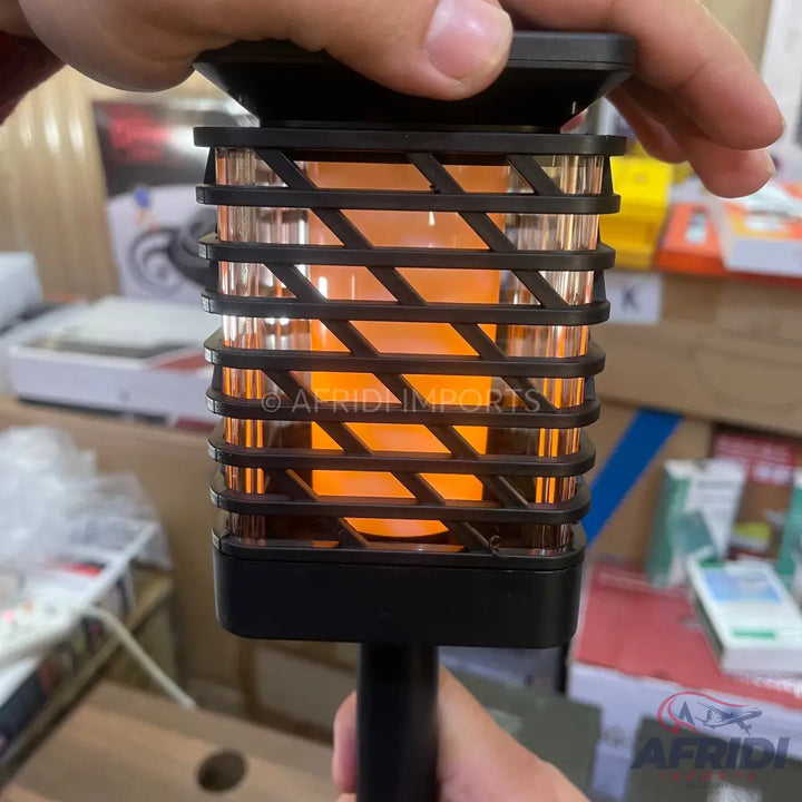 A black solar-powered LED flickering flame torch with a clear, ribbed casing.
