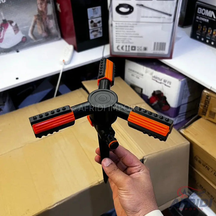 Black and orange 4-arm rotating garden sprinkler.