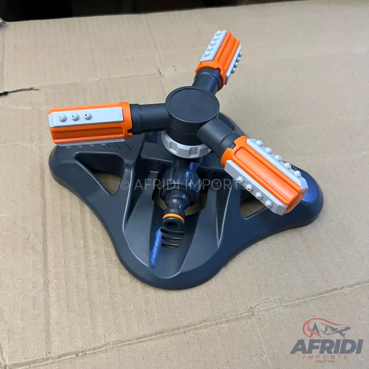 A three-arm rotating garden sprinkler with adjustable spray nozzles on each arm, a dark gray base, and orange and gray accents.