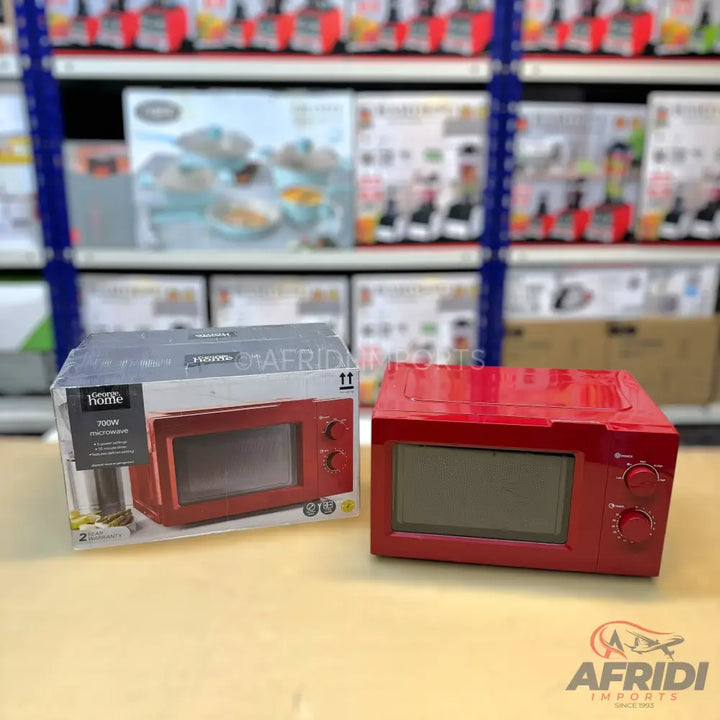A red microwave oven, still in its packaging, with another identical red microwave oven next to it.